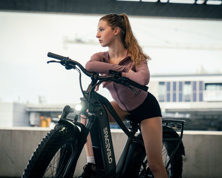 Young woman poised on a SPACEVELO Terra X1 electric bike, reflecting satisfaction and style in an urban setting, embodying eco-friendly values and exceptional design that promotes fitness and compliments.